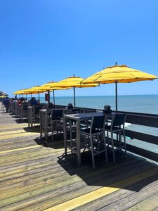 line of yellow umbrellas in tables on pier